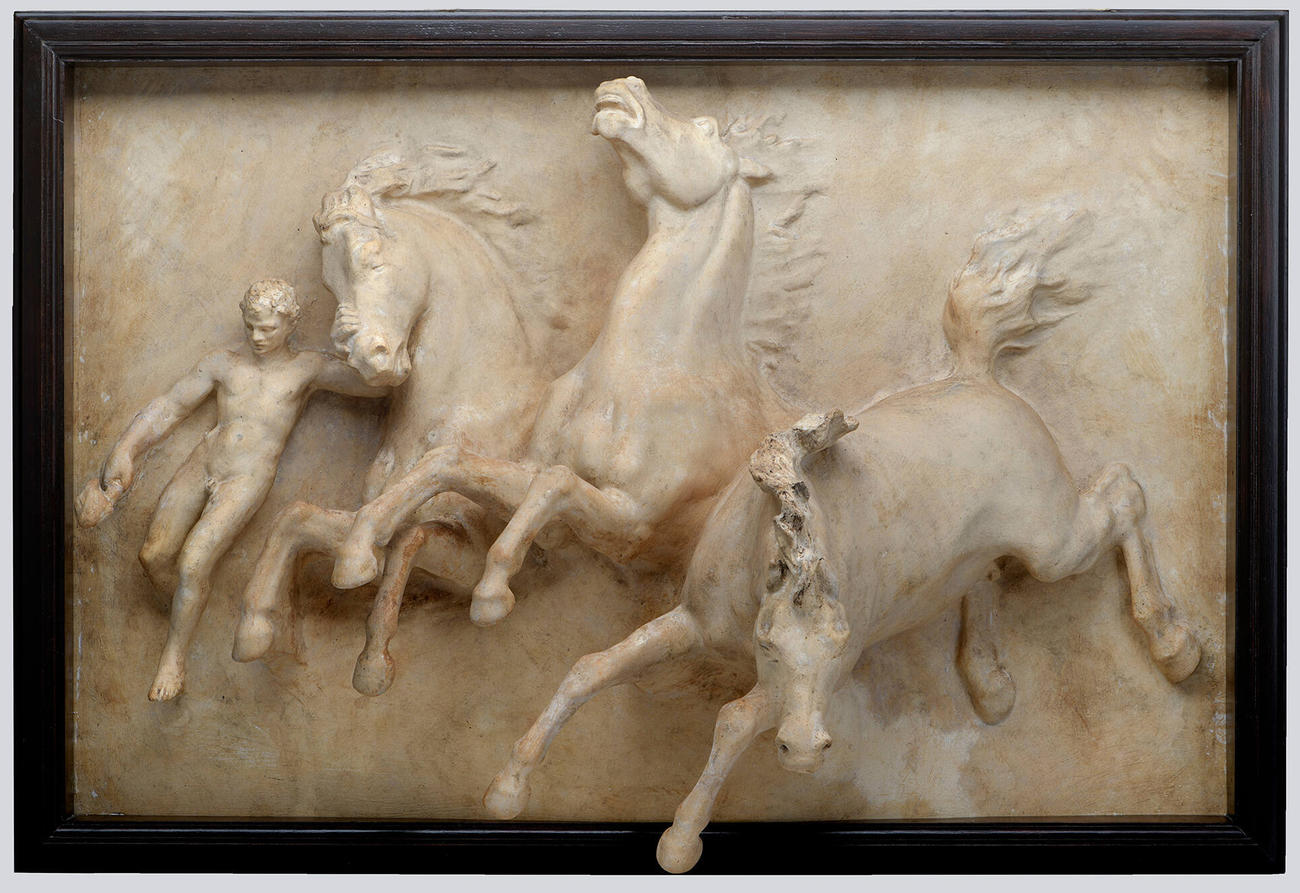 A plaster cast of three charging horses alongside a human figure 