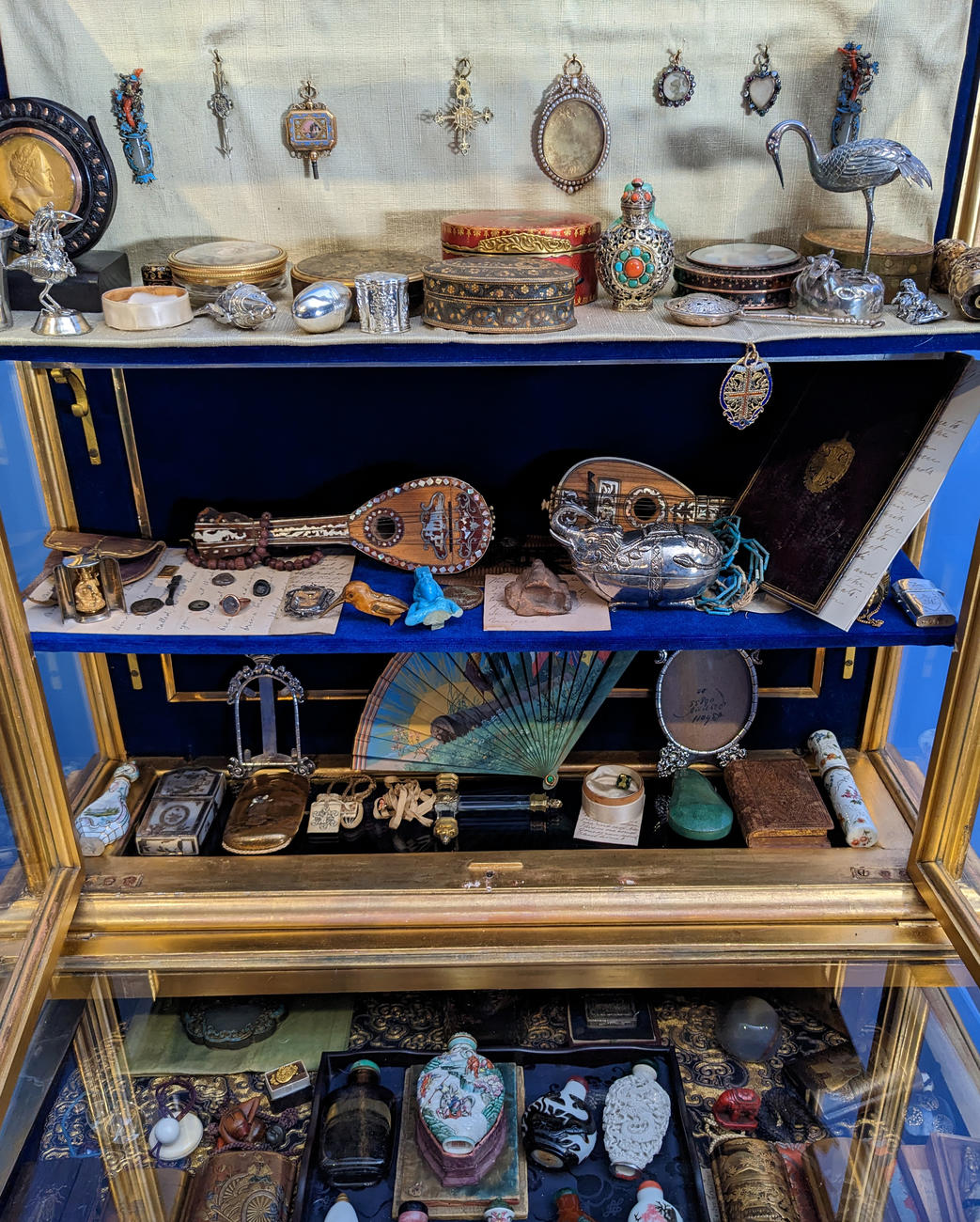 An image of a gilt vitrine from the Gardner Museum showing four levels of small objects displayed in its interior after the objects had been conserved.