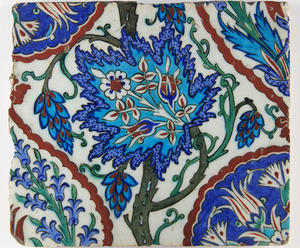 A square blue, white, red, and green ceramic tile with a central stylized grape leaf.