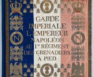 Front view of a square flag from Napoleon’s Imperial Guard embroidered in gold thread on blue, white, and red silk cloth, edged with gold fringe.
