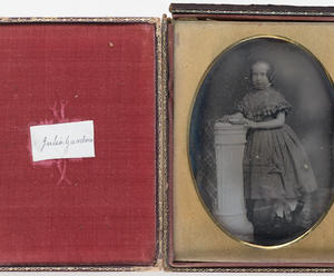 An open case lined with red velvet contains an oval black and white photograph of a girl about 9 years old identified as Julia Gardner. She is standing and wearing a 19th century dress and hairstyle.