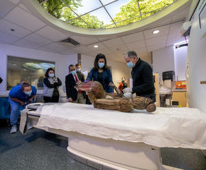 The Guanyin sculpture lays on the CT scanning bed inside the machine while medical staff tests the positioning with a laser alignment system.  