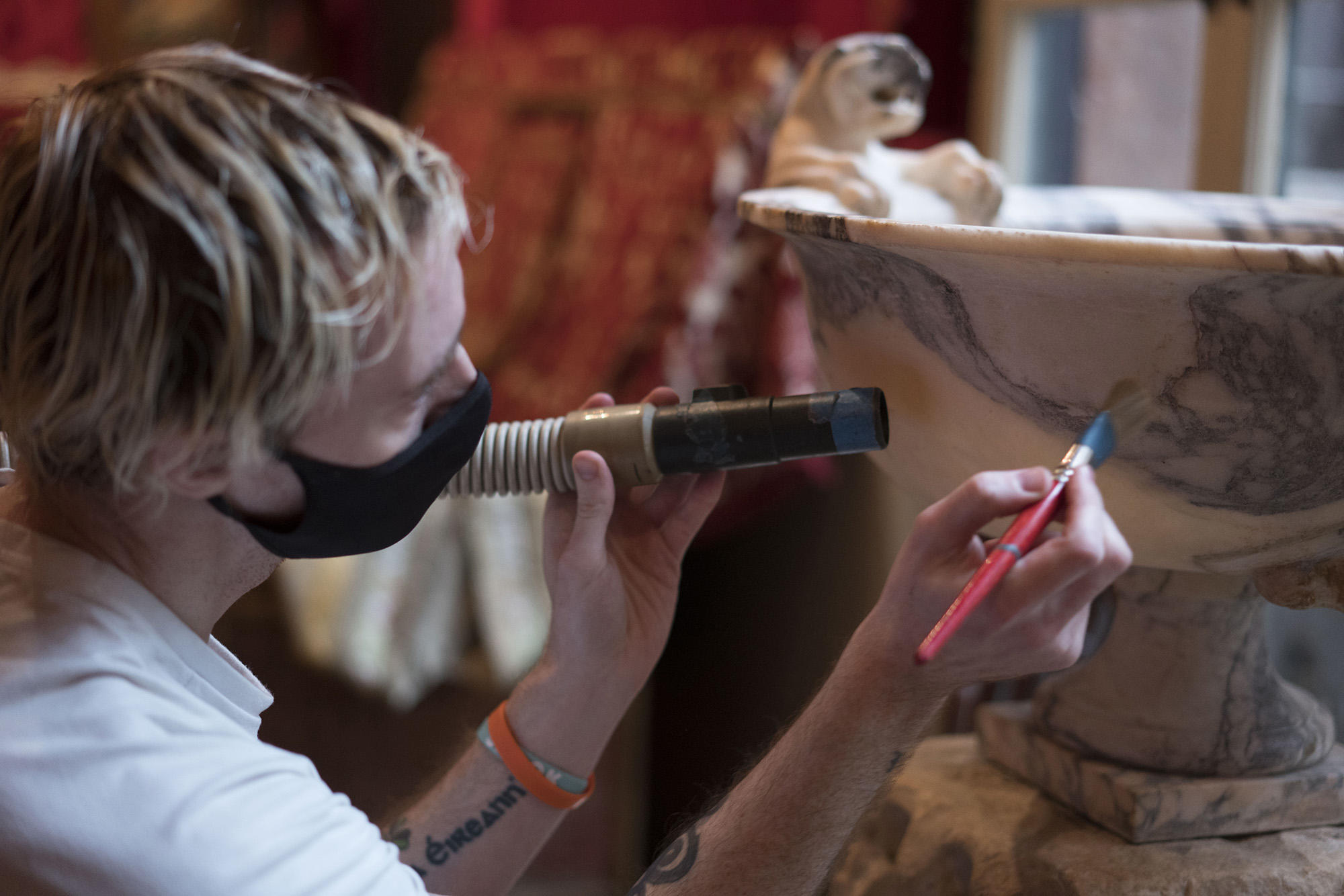 Joe McGrath uses a soft brush to remove surface dust from a bowl in the Raphael Room, 2021