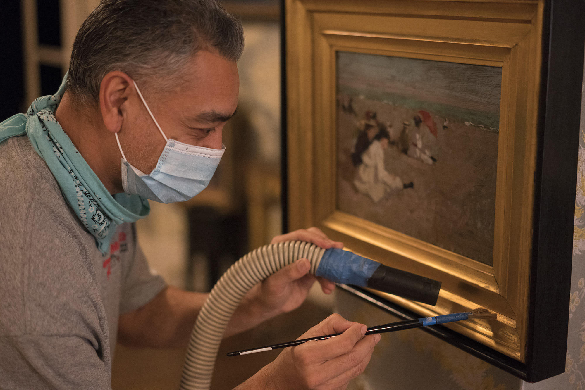 Prabhat Srestha gently dusts a gilded frame in the Blue Room, 2021