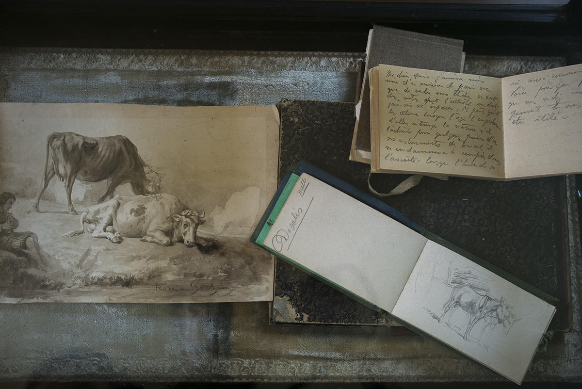 Two sketches and a journal on a dark table