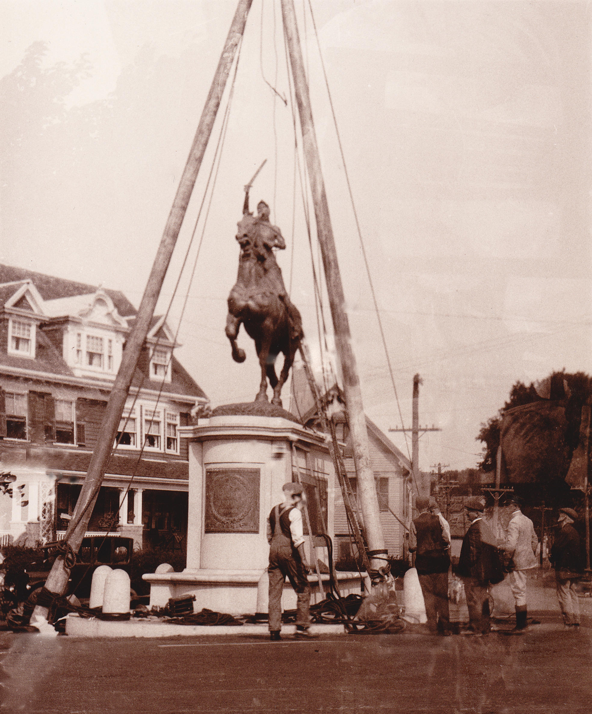 A photograph of builders placing a statue on a pedestal