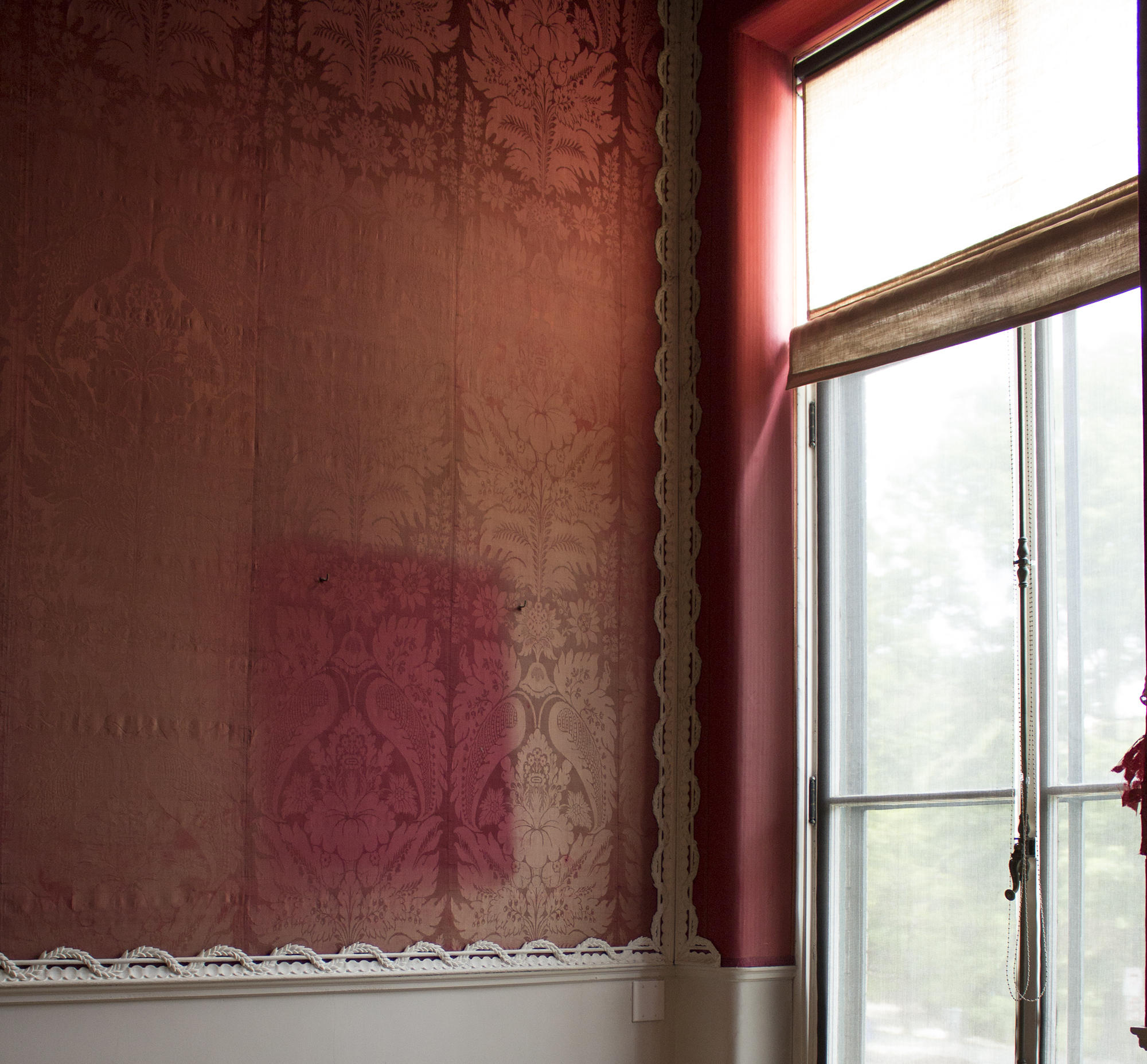 Red silk walls with noticeable light discoloration.