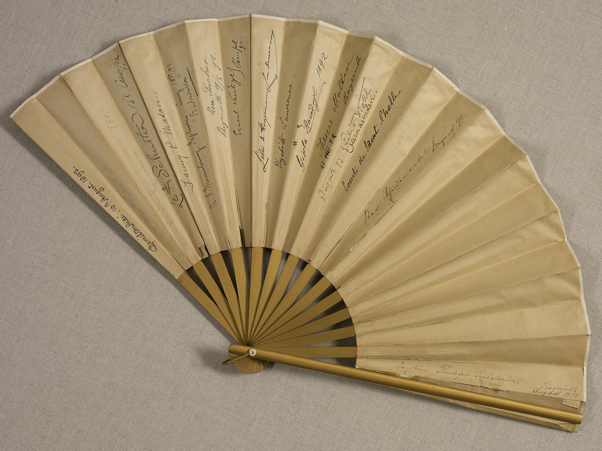  A tan folding fan with some writing.