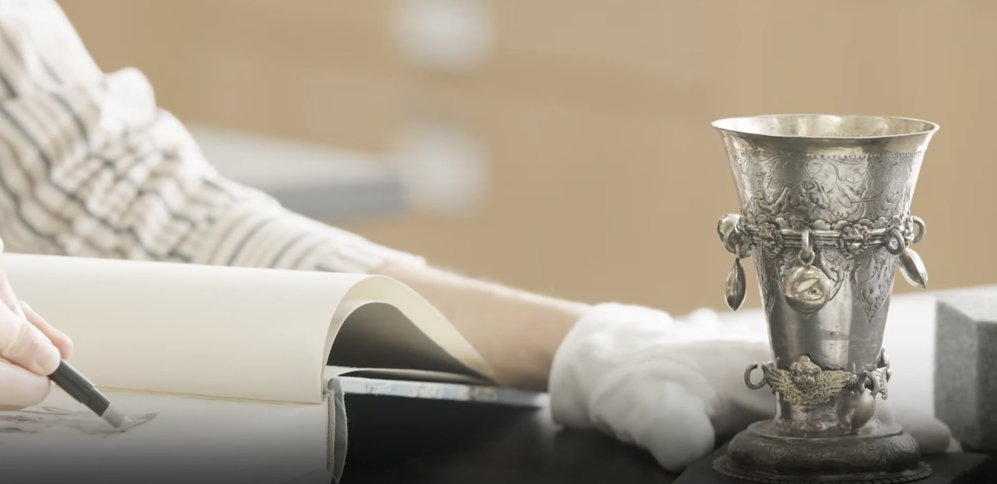 A person restoring an old silver cup.