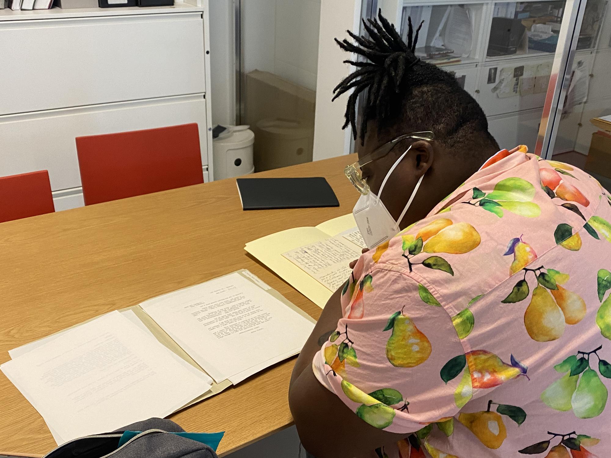 Porsha Olayiwola sitting at a table reading over papers. 