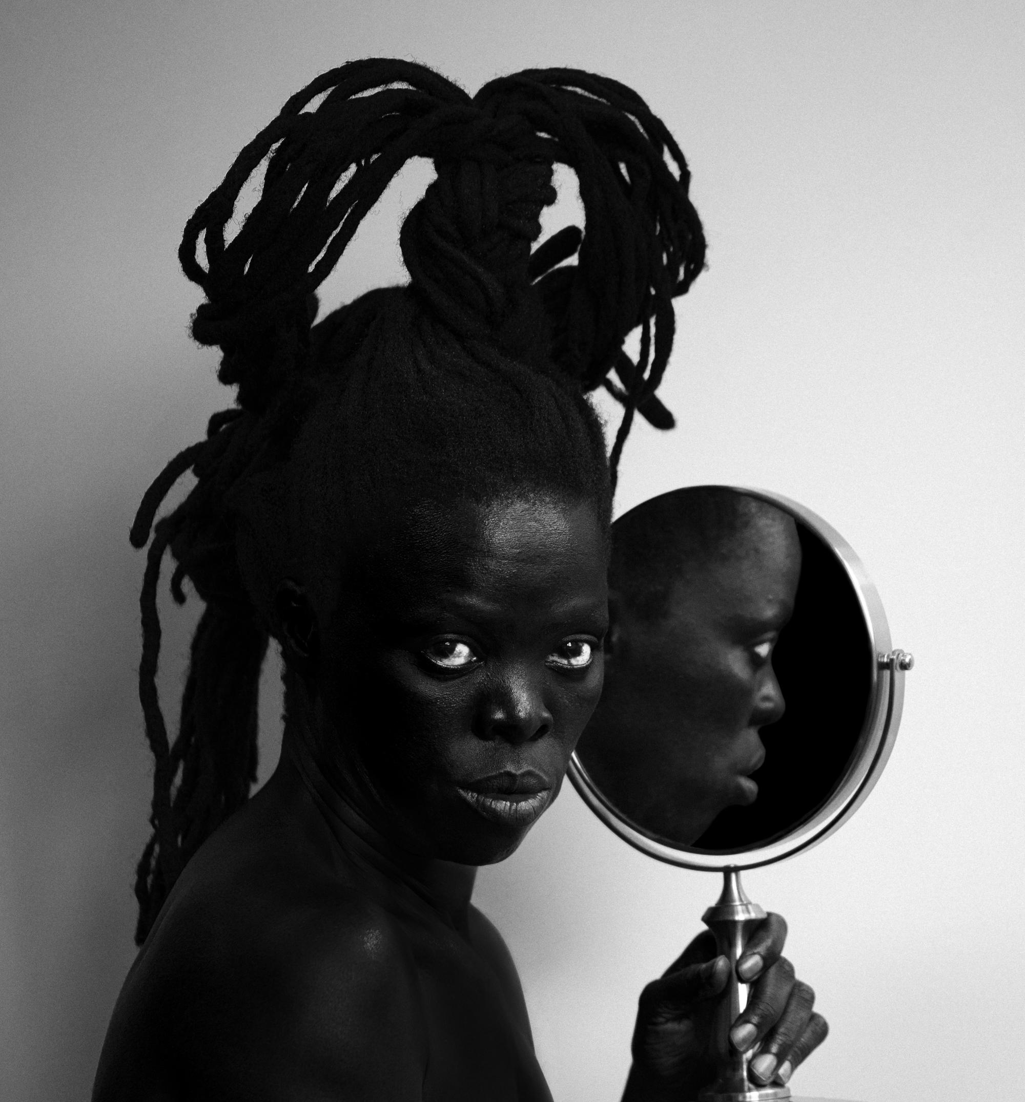 A photo of a person with a mirror in one hand looking at the camera. 