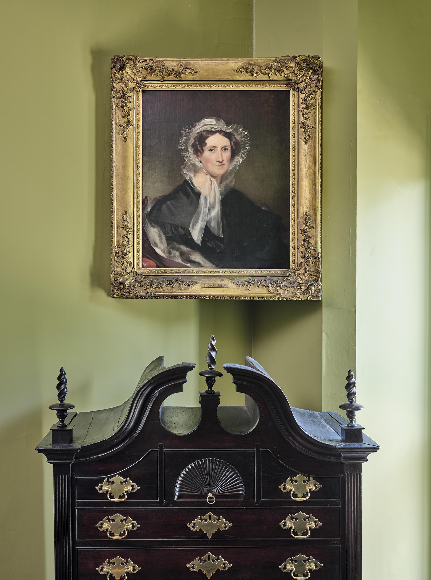 A portrait of Isabella Tod Stewart above an armoir.