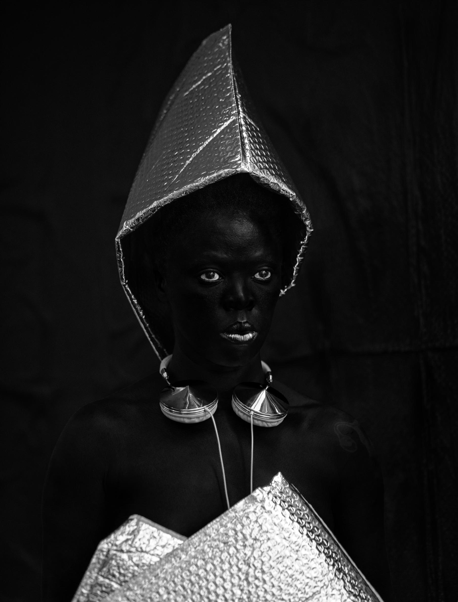 A black and white photo of a person with cushioned envelopes on the top of their head and as a top.