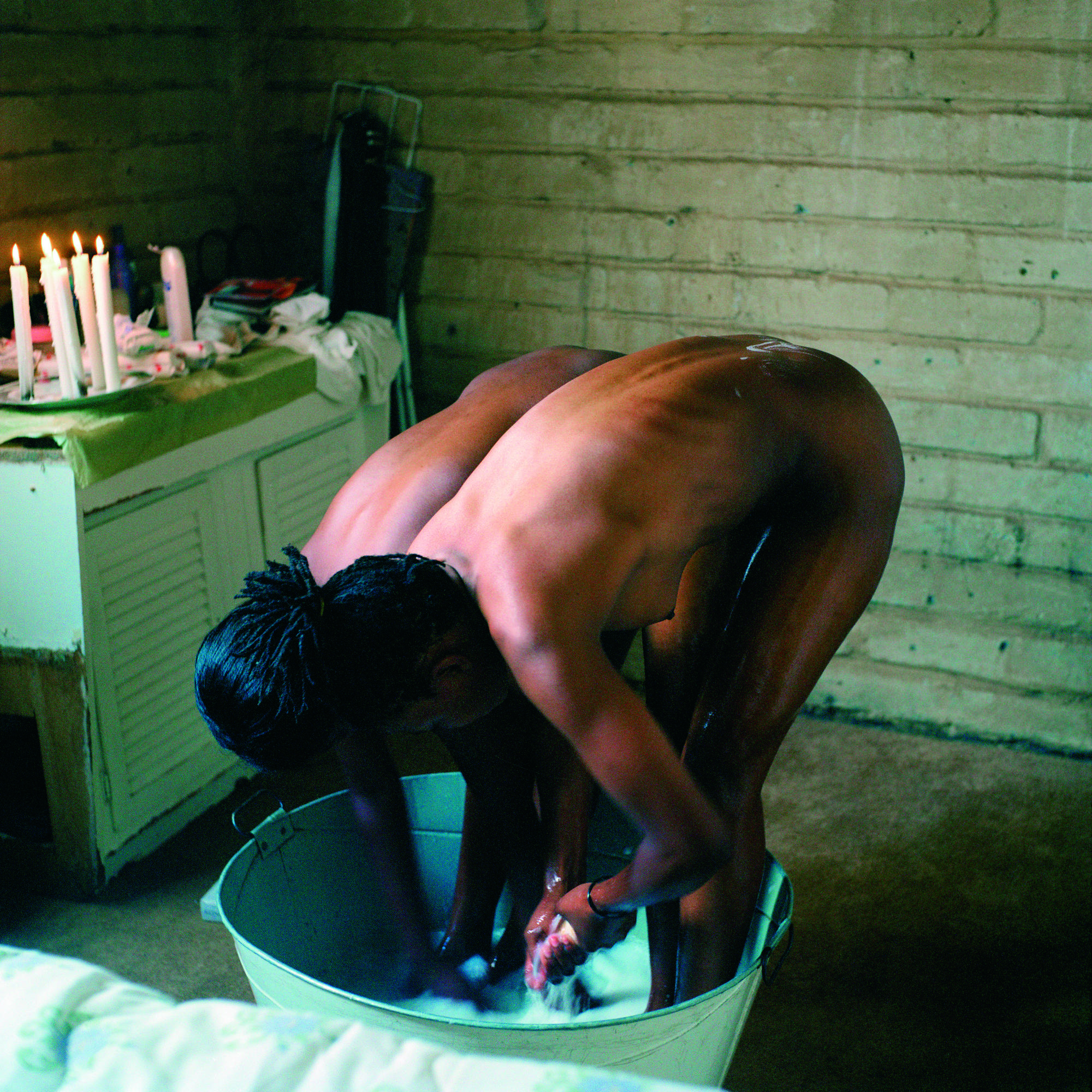 Two people naked bathing themselves in a wash bin.