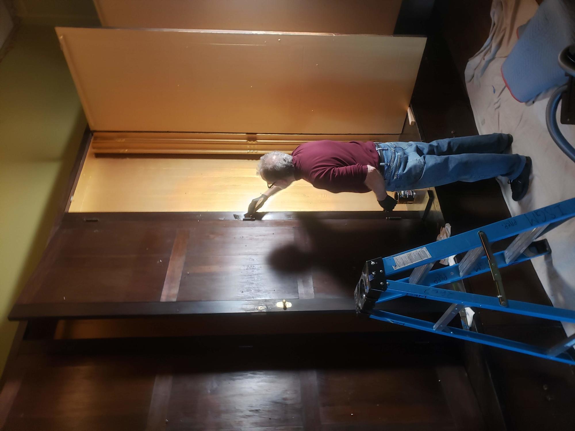 Preparator David Kalan applying a finish to the Short Gallery cabinet exteriors.