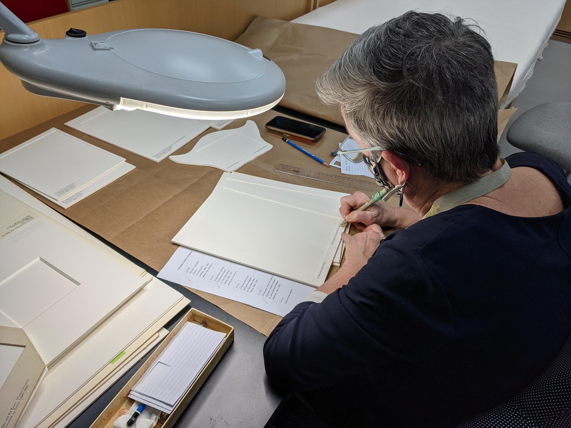  Artist Mary DePalma hand-captioning new mats for the Short Gallery works on paper.