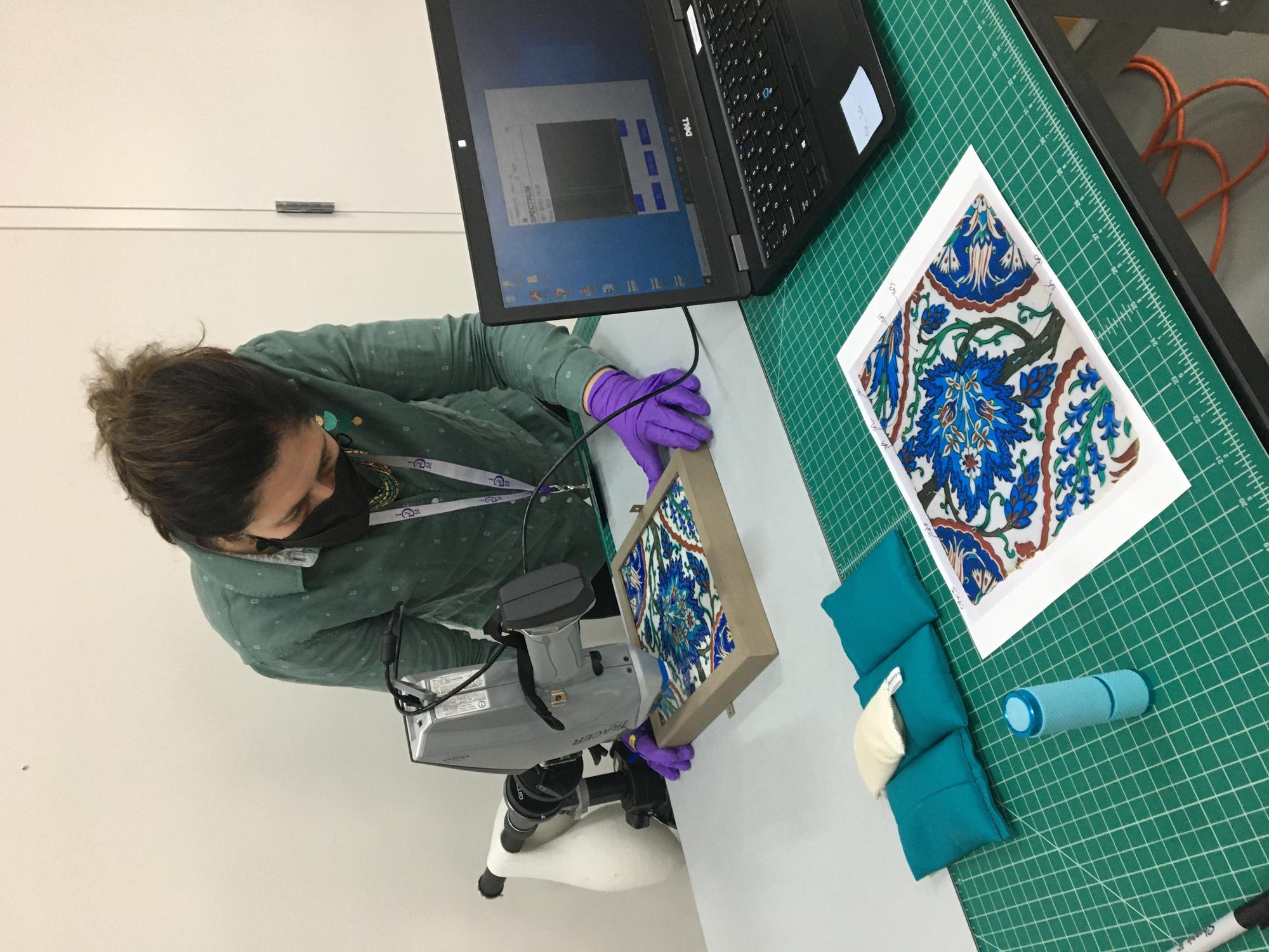 A woman uses a portable x-ray fluorescence spectrometer to analyze the glaze colorants on the Turkish tile.