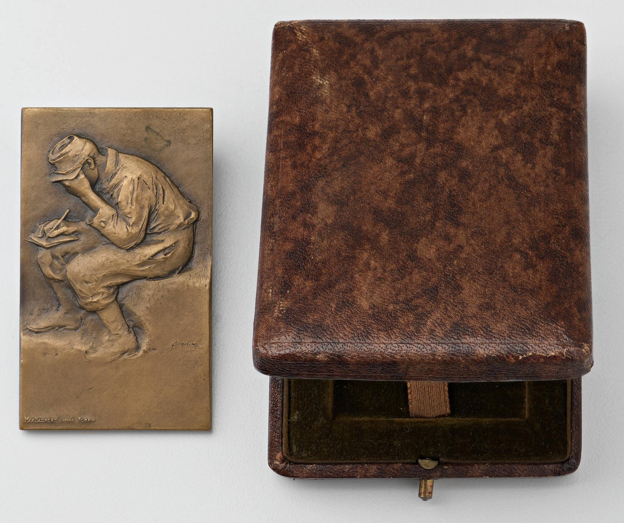 Bronze plaquette with high relief design showing a seated soldier with his head down, enclosed in a hinged leather case.