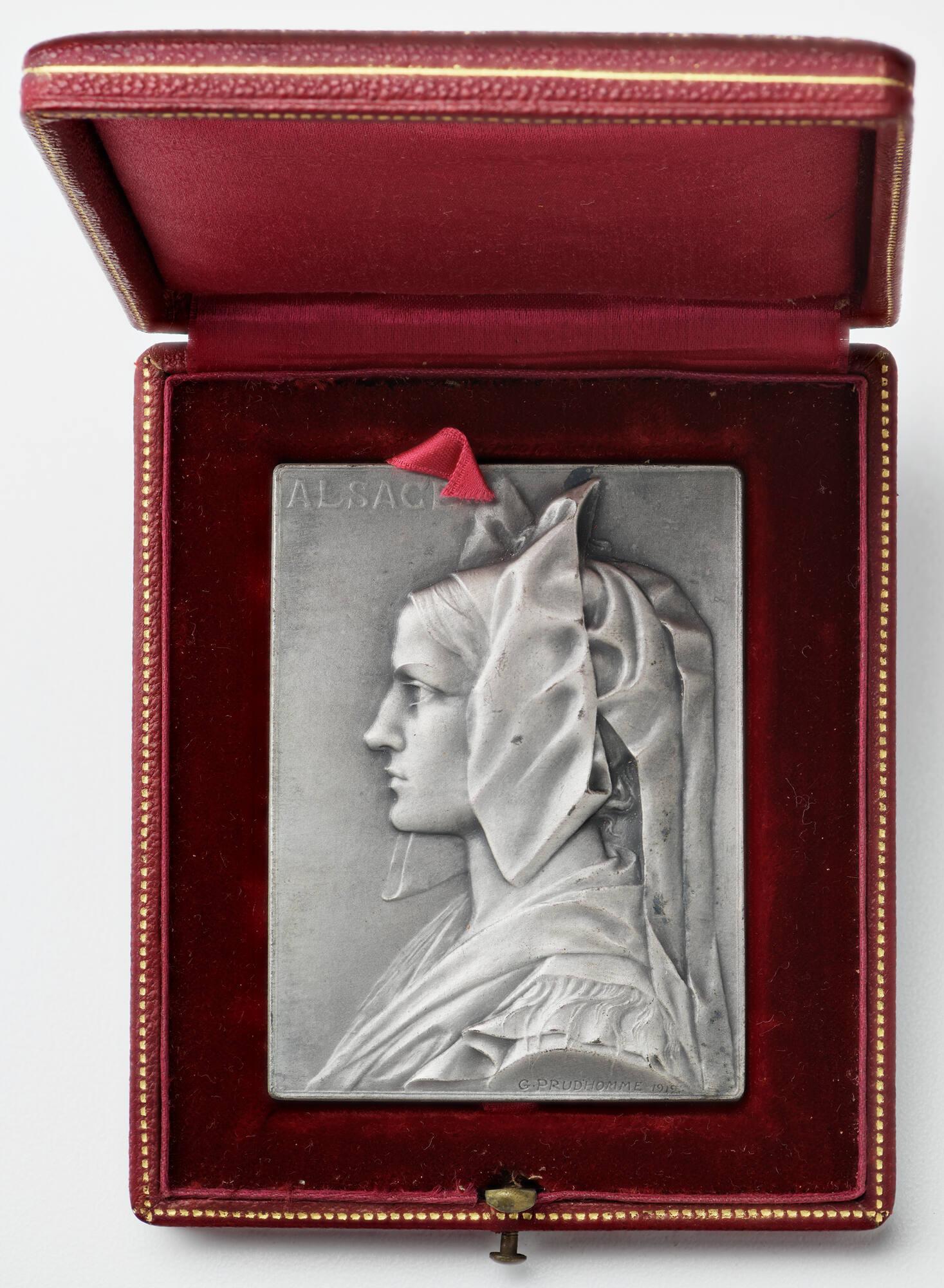 Silver plaquette with the profile of a woman's head and shoulders in high relief, set in a hinged box.
