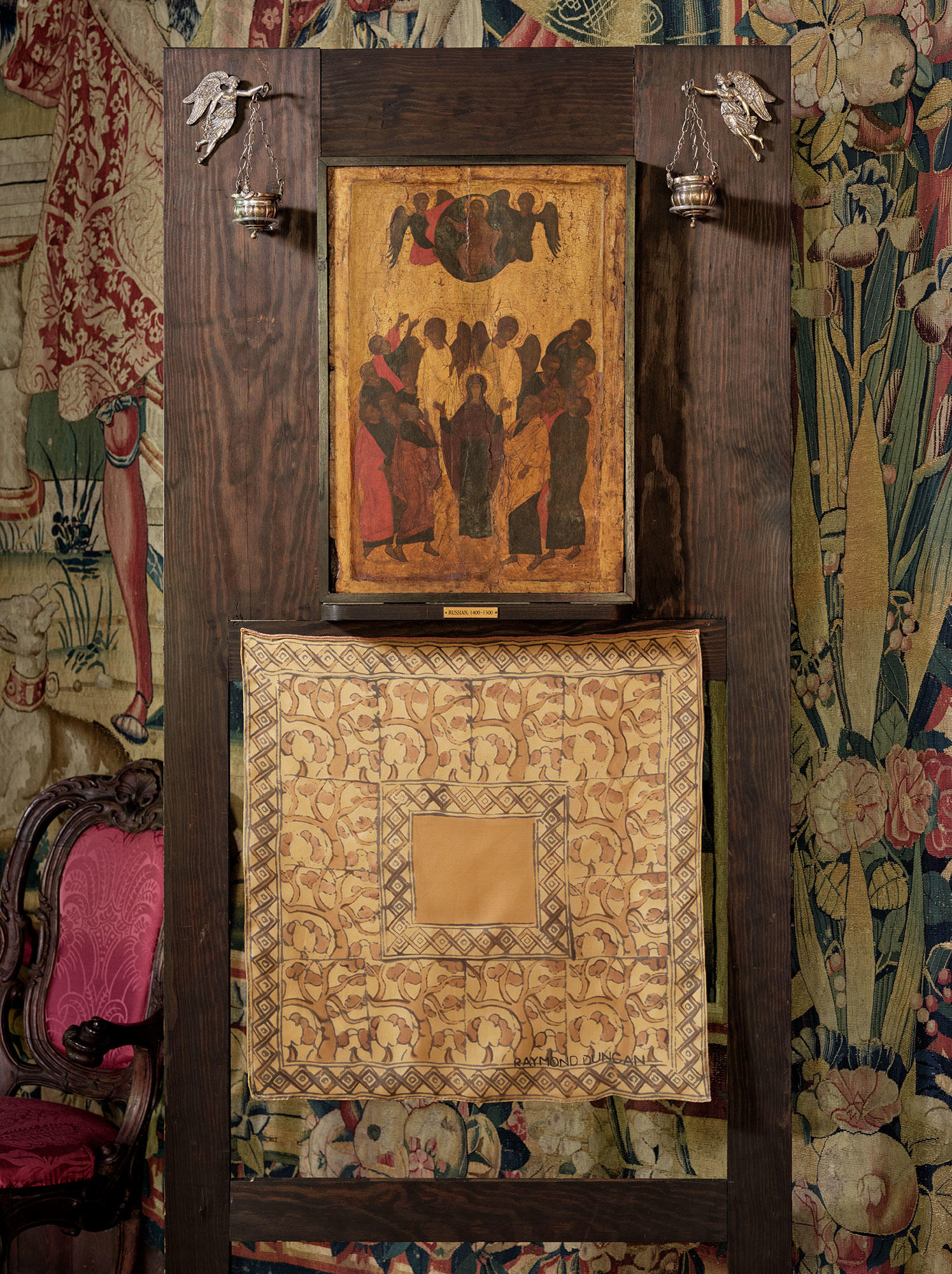 A wooden easel with a painting of the ascension of the Virgin, a pair of silver holy water stoups and a scarf with an abstract design of trees.