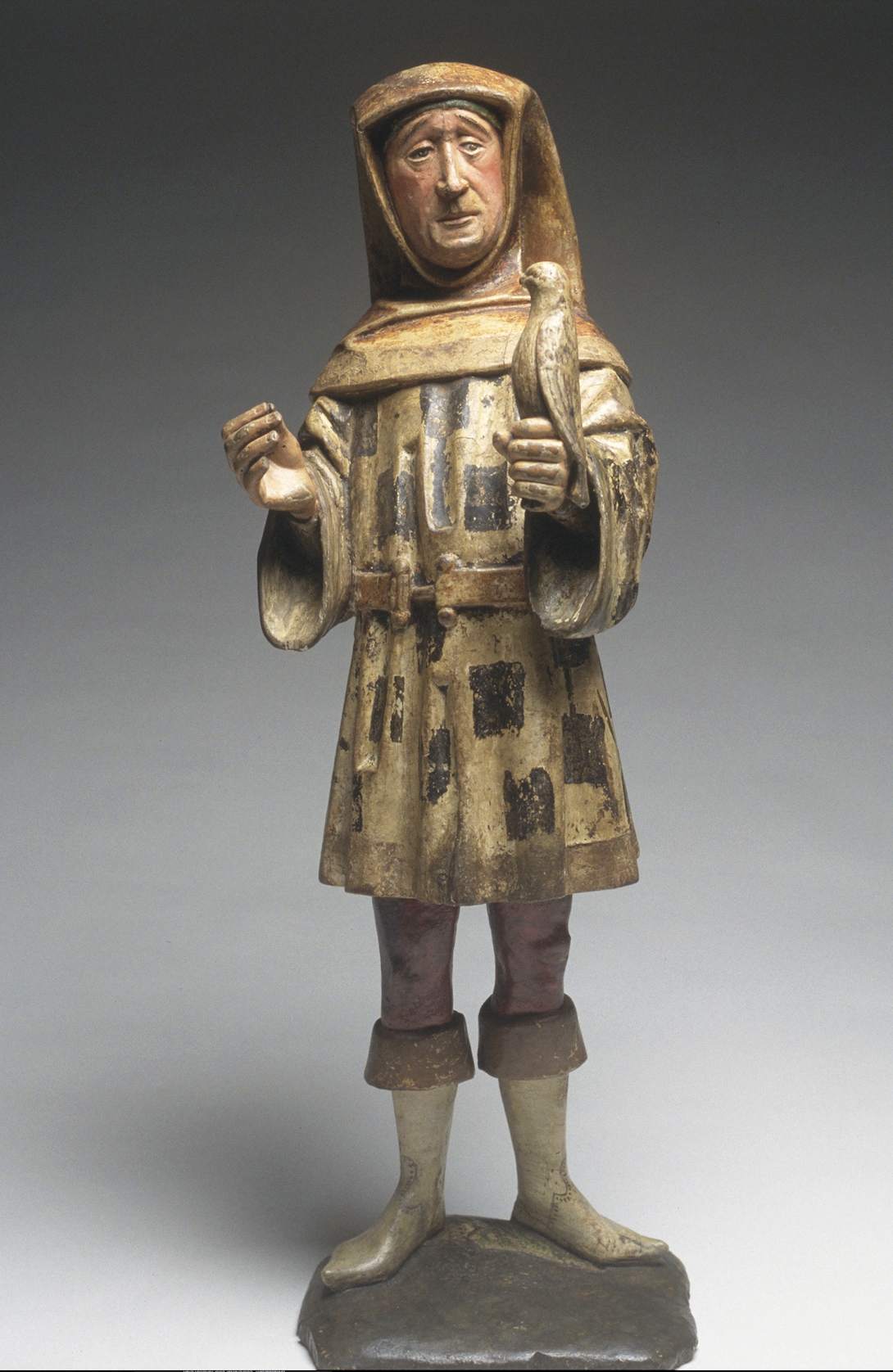 Painted wood sculpture of the Falconer, featuring a standing man in historic dress holding a falcon in his left hand.