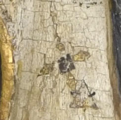Detail of decoration on Saint Agnes’ white mantle depicting black square in center with diamond-shaped gold lozenges at the top and sides, creating a cross pattern.