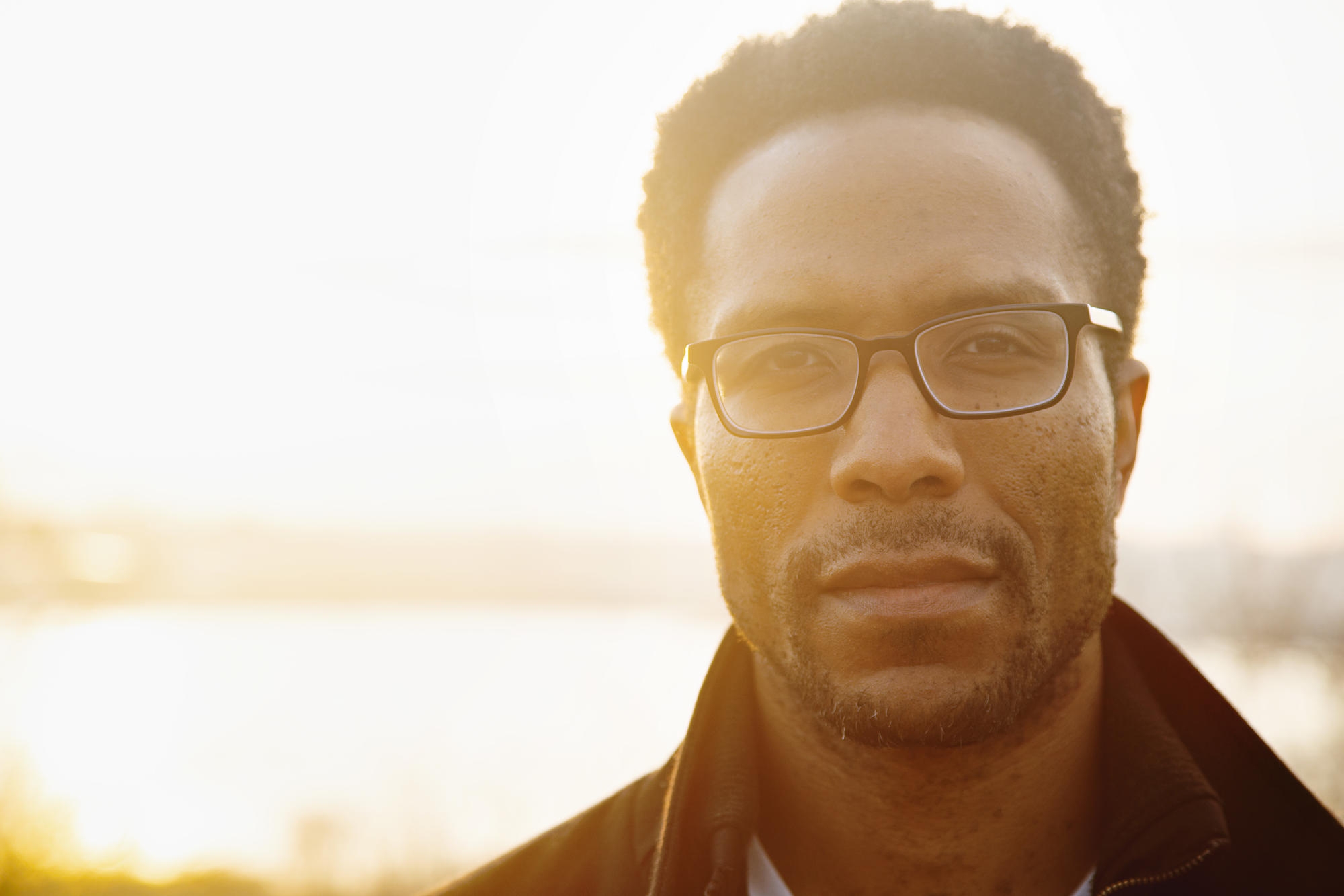 Headshot of man with glasses. Sunset with blurred background.