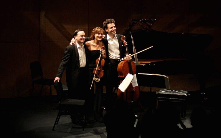 Photo of three musicians on a stage with a cello and violin.  