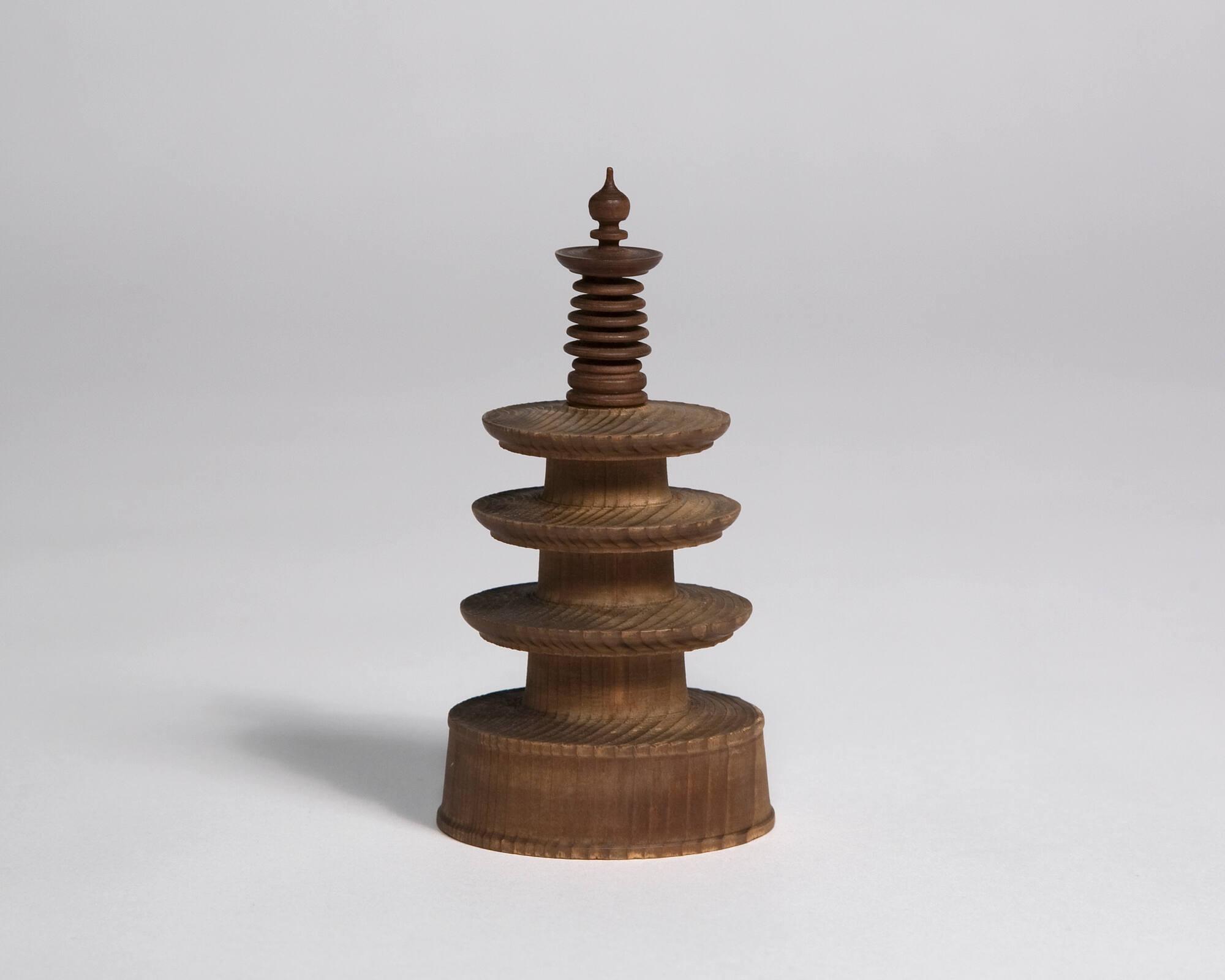 Small carved wooden pagoda with a round base and pointed at the top, constructed by Nirro Chunosuke.