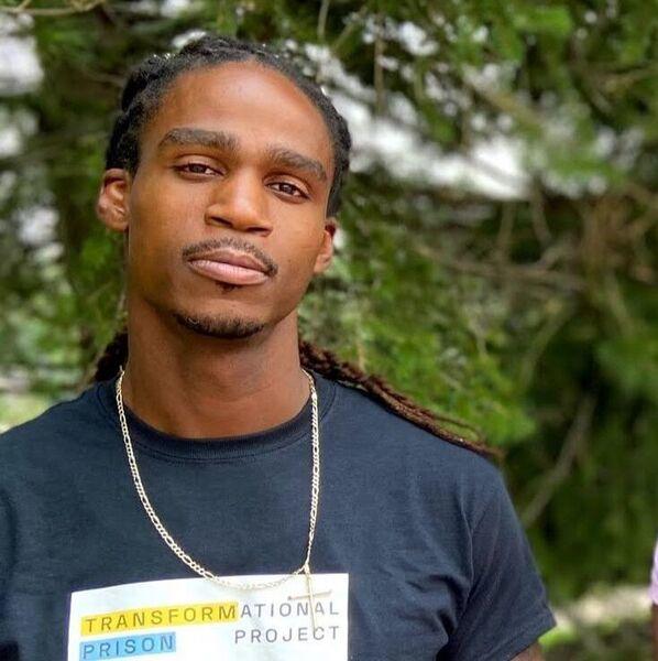 Photo of a man wearing a silver chain and a blue graphic t-shirt