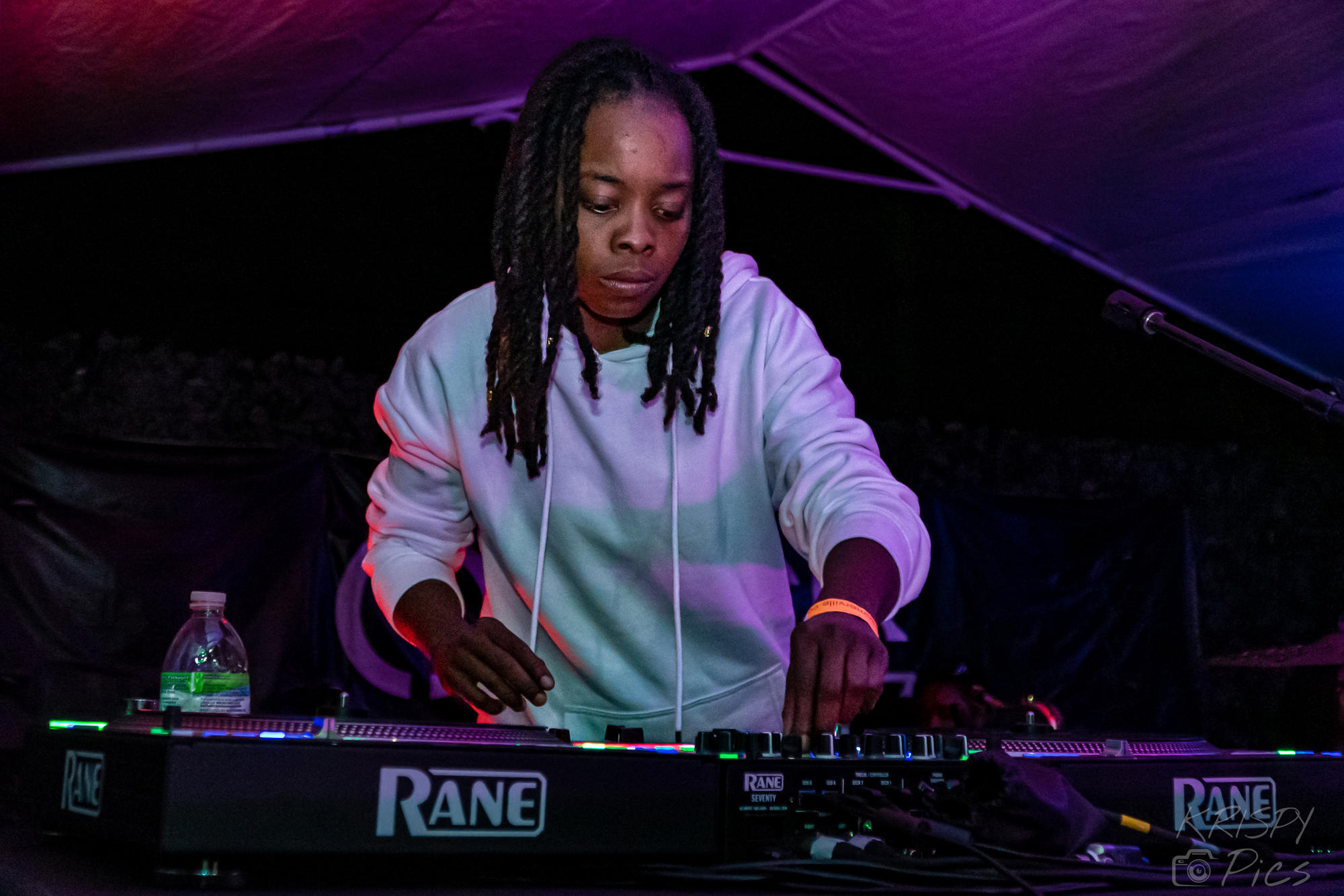 Photo of a women in a grey sweatshirt at a DJ booth. 