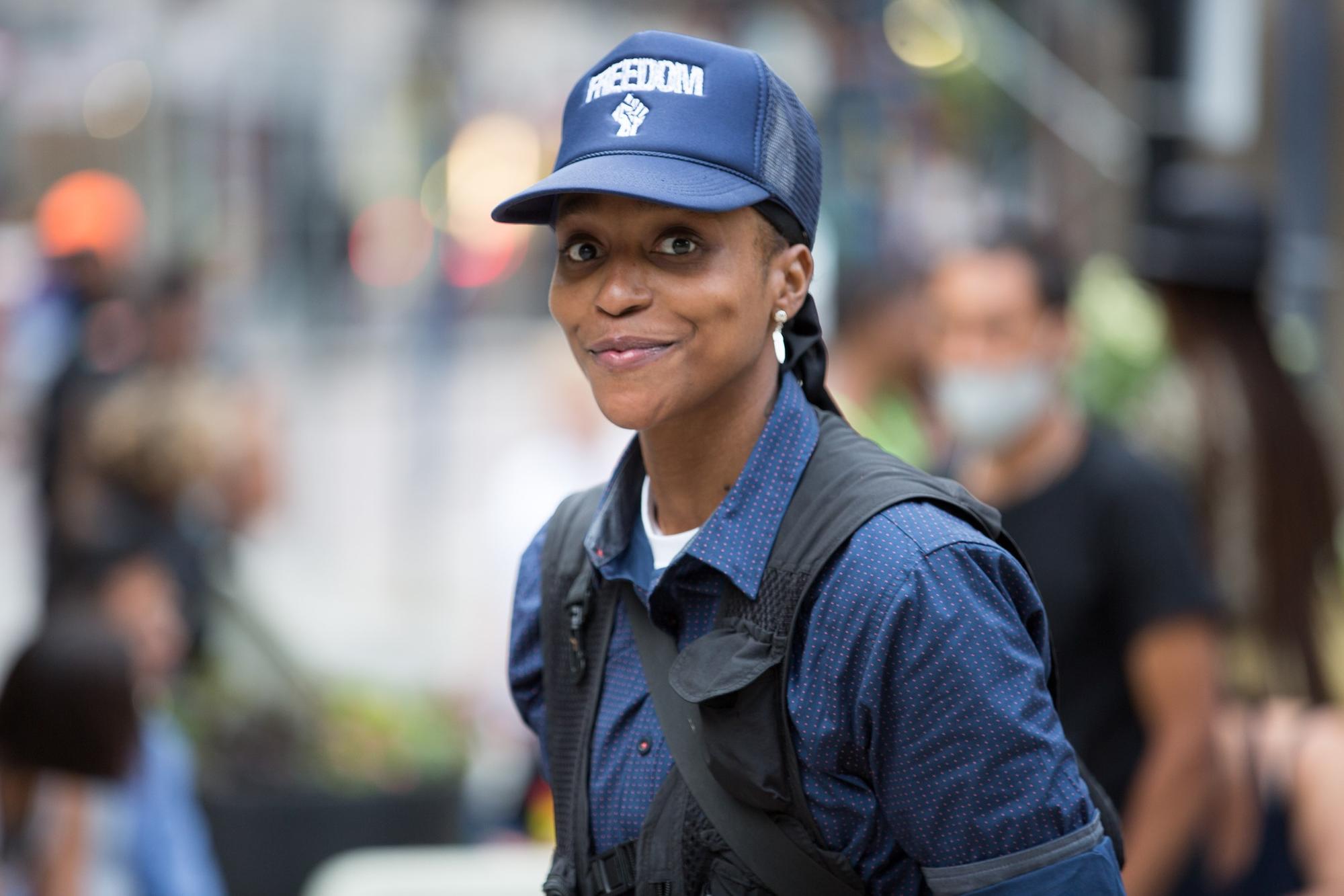 Photo of a person in a blue hat and a blue shirt with a blurred background. 