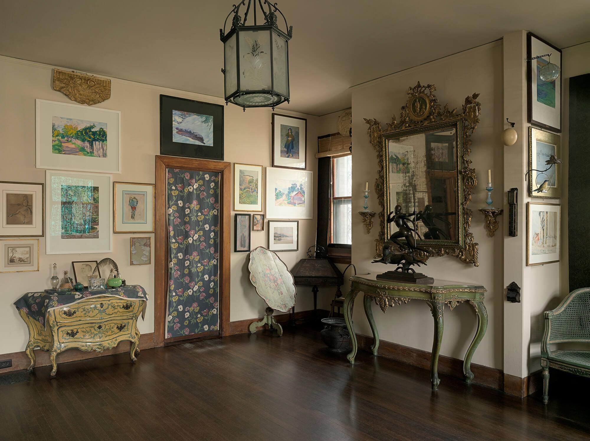 A wall in the Macknight Room at the Isabella Stewart Gardner Museum showing artwork on the walls and furniture.