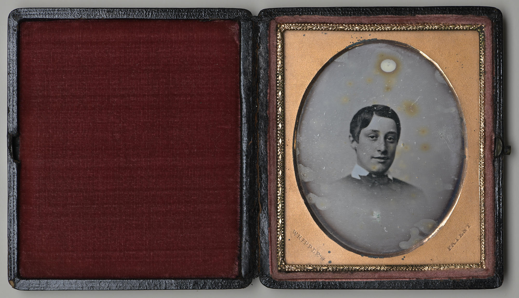 An open case lined with red velvet contains an oval black and white photograph of a boy about 12 years old identified as John L. Gardner, Jr.  He is dressed in 19th century attire.