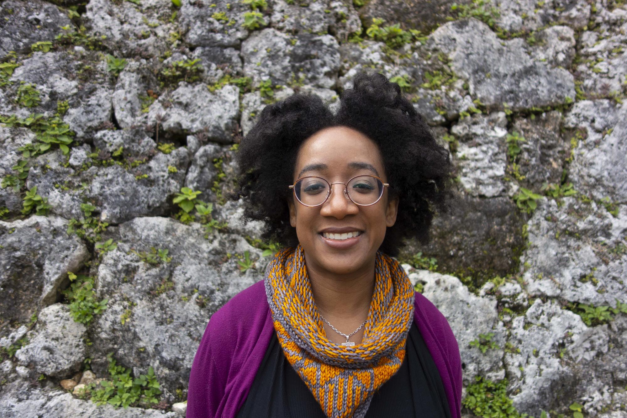 Photo of a woman against a rocky background. 