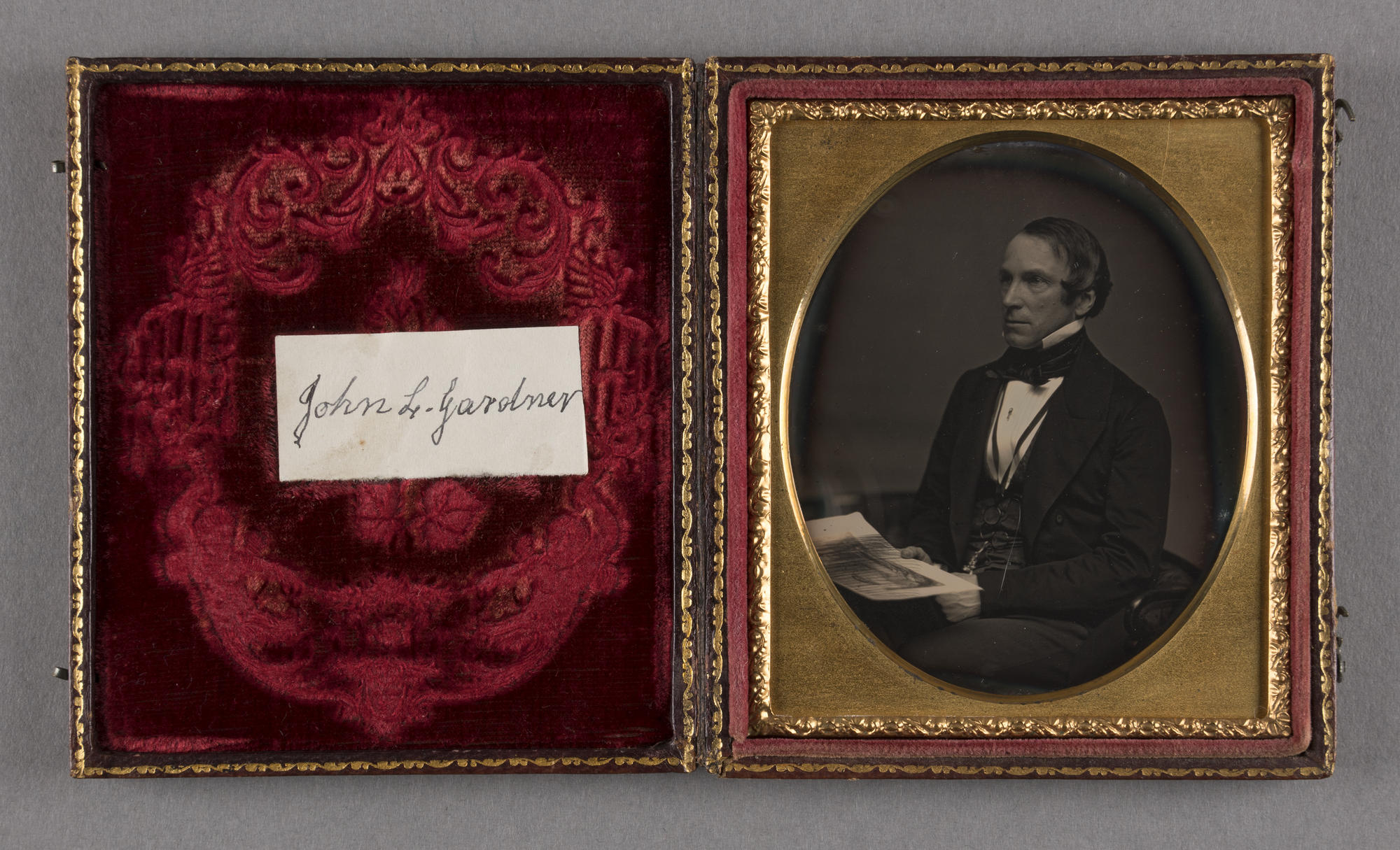 An open case lined with red velvet contains an oval black and white photograph of a middle aged man, identified as John Lowell Gardner Sr.. He is seated and dressed in 19th century attire.