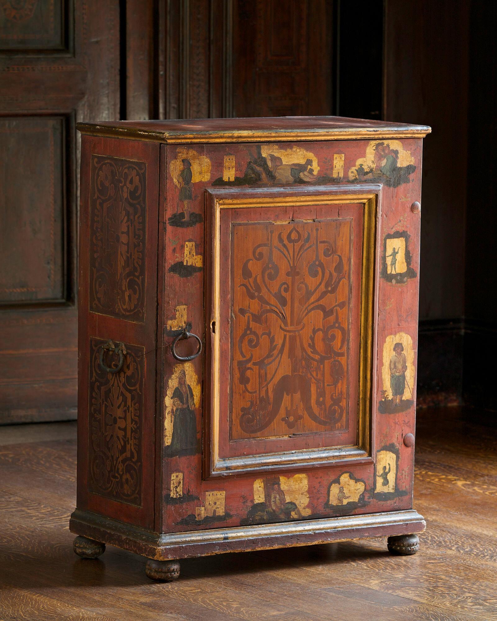 Eighteenth century Italian wooden cabinet from the Trentino-Alto Adige region of Italy. The cabinet has a door in the front, and it’s painted red with gold decoration and pastoral figures.
