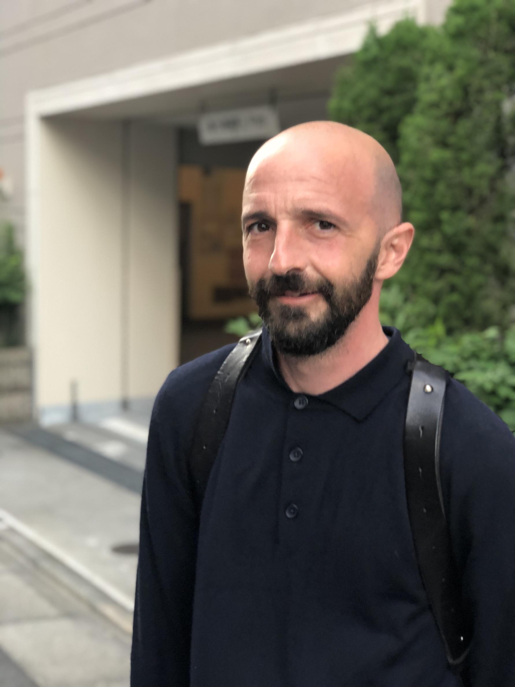 Photo of a person in a black shirt standing outside. 