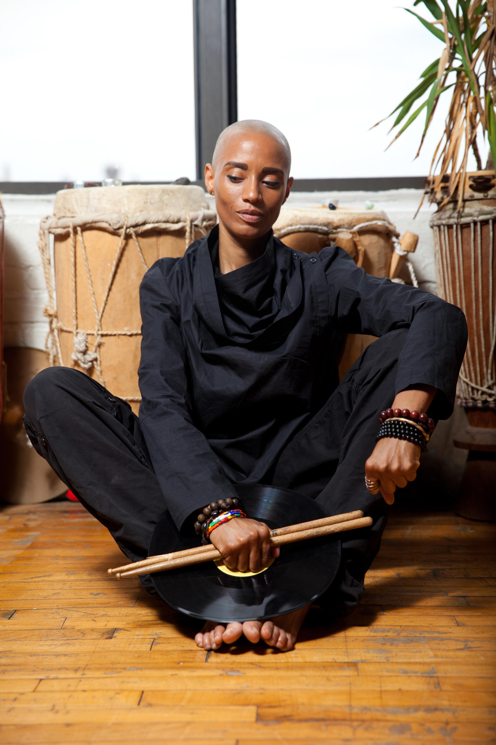 Photo of a person sitting on the floor in front of drums.