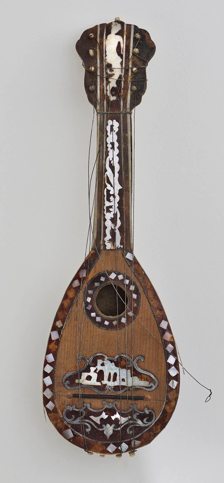 A miniature stringed instrument at the Isabella Stewart Gardner Museum made of wood and tortoise shell, with mother-of-pearl designs shown before conservation.