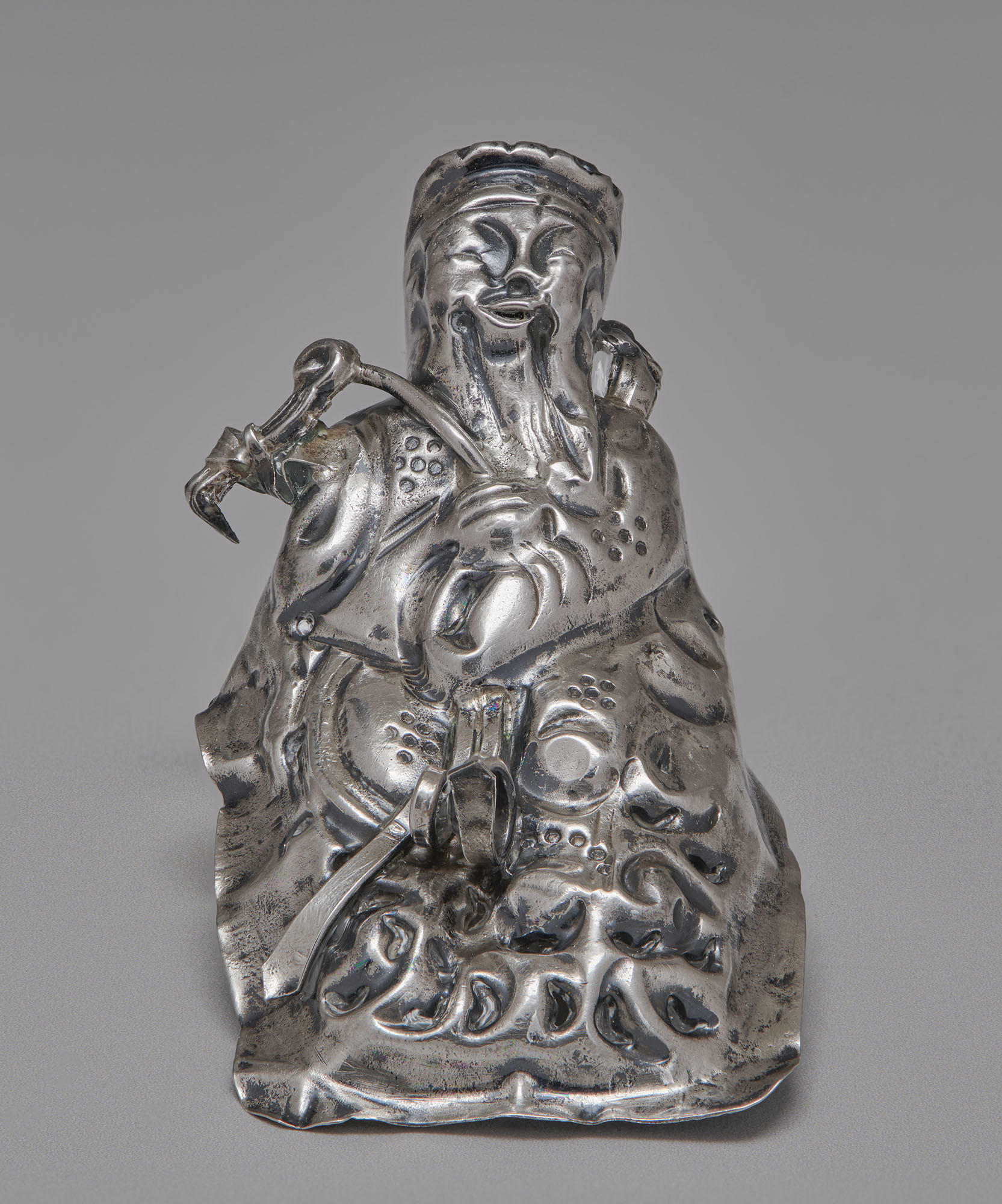 A clean silver object with a high relief design of a figure wearing a robe and headdress shown after conservation at the Isabella Stewart Gardner Museum.