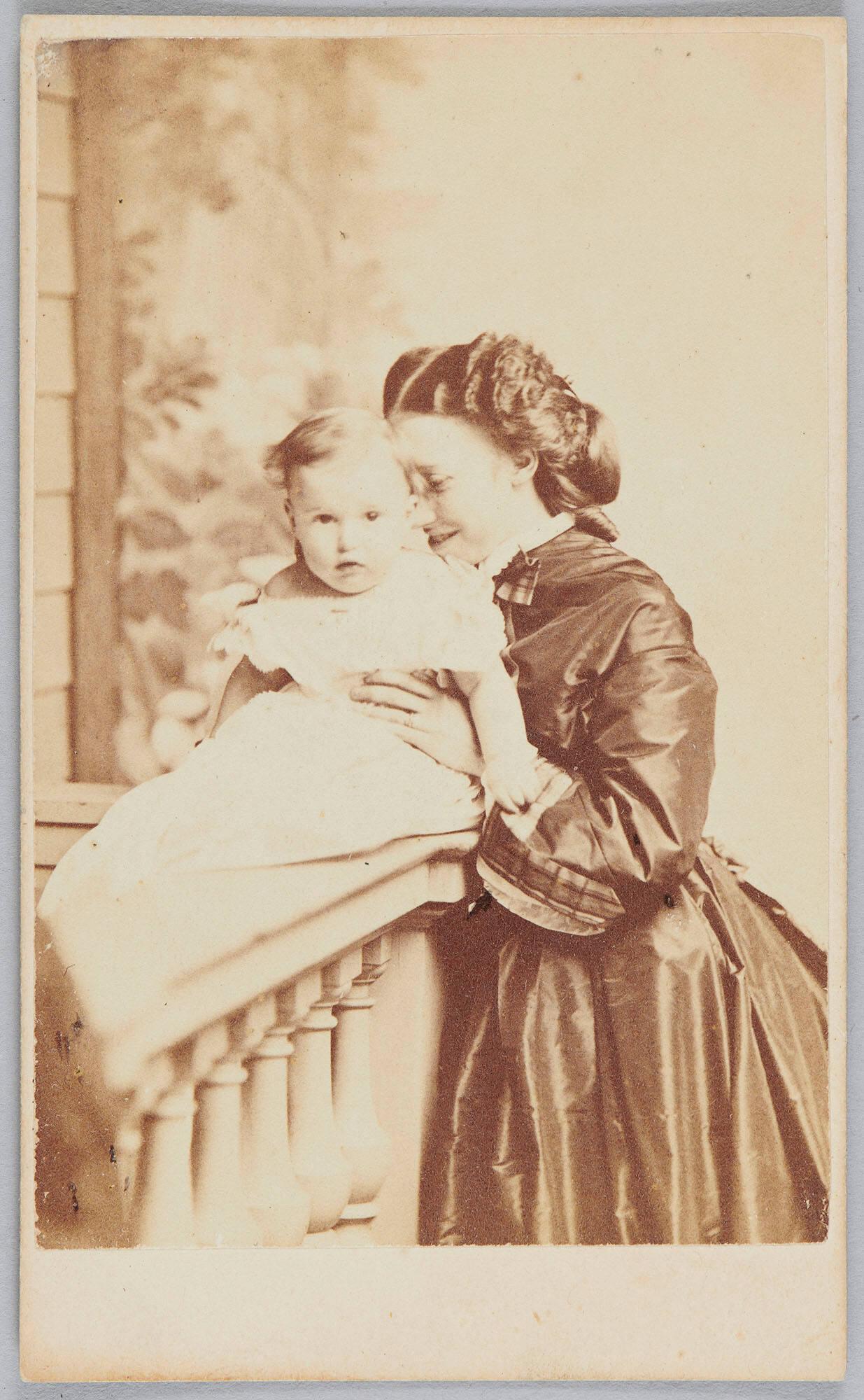A sepia toned photograph of a white woman with dark hair and 19th century dress smiling and holding a baby. The woman, Isabella Stewart Gardner, is nuzzling the head of her son, Jackie.