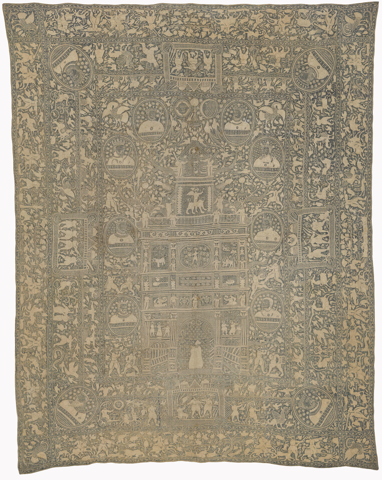 An embroidered wall hanging of cream colored thread on a dark blue background. Three rows of borders with people, plants, animals, and mythological creatures surround a central field with an arch and eight busts of kings.