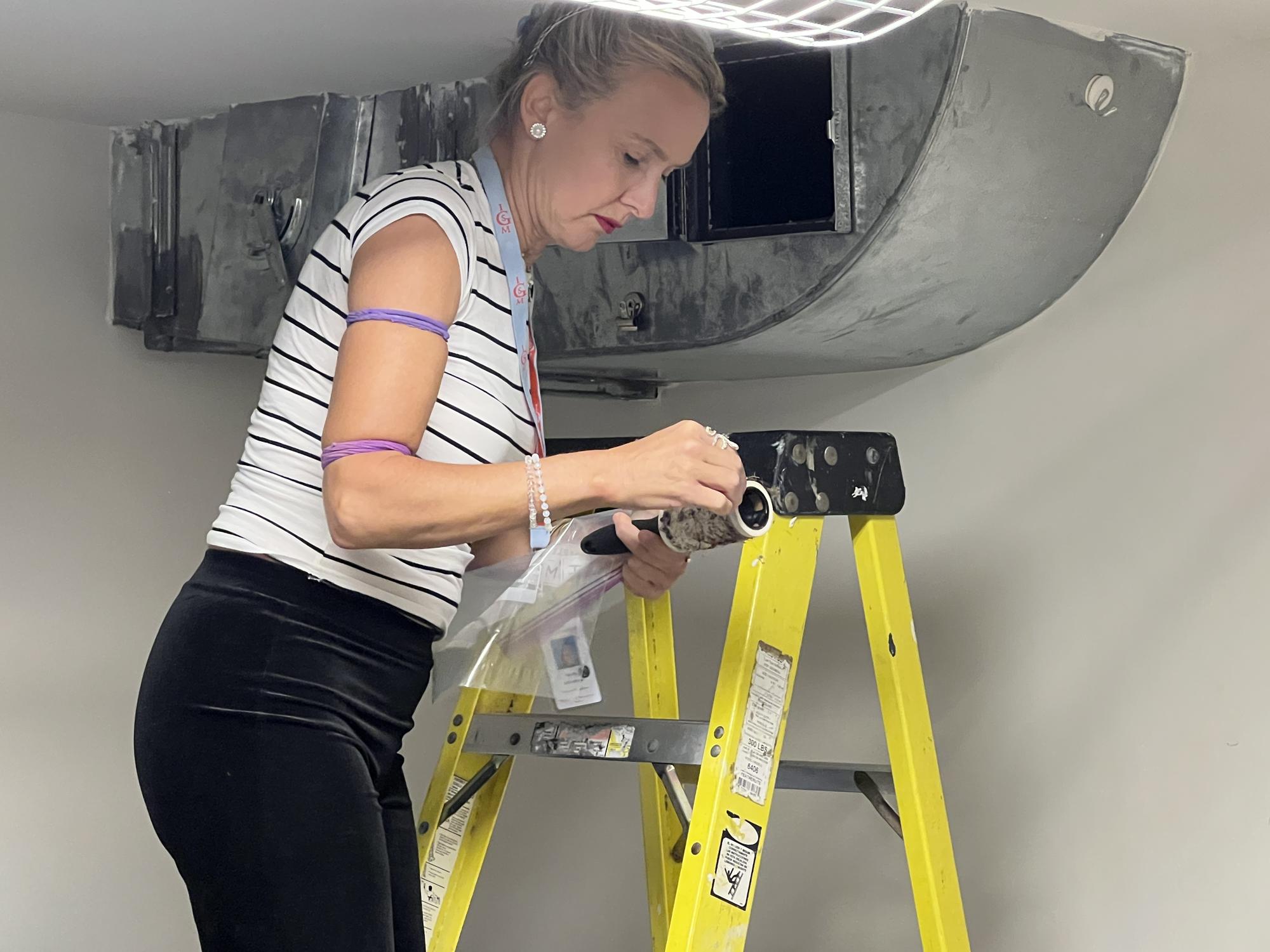 Natalie Jeremijenko collecting samples from a vent in the basement, 2022