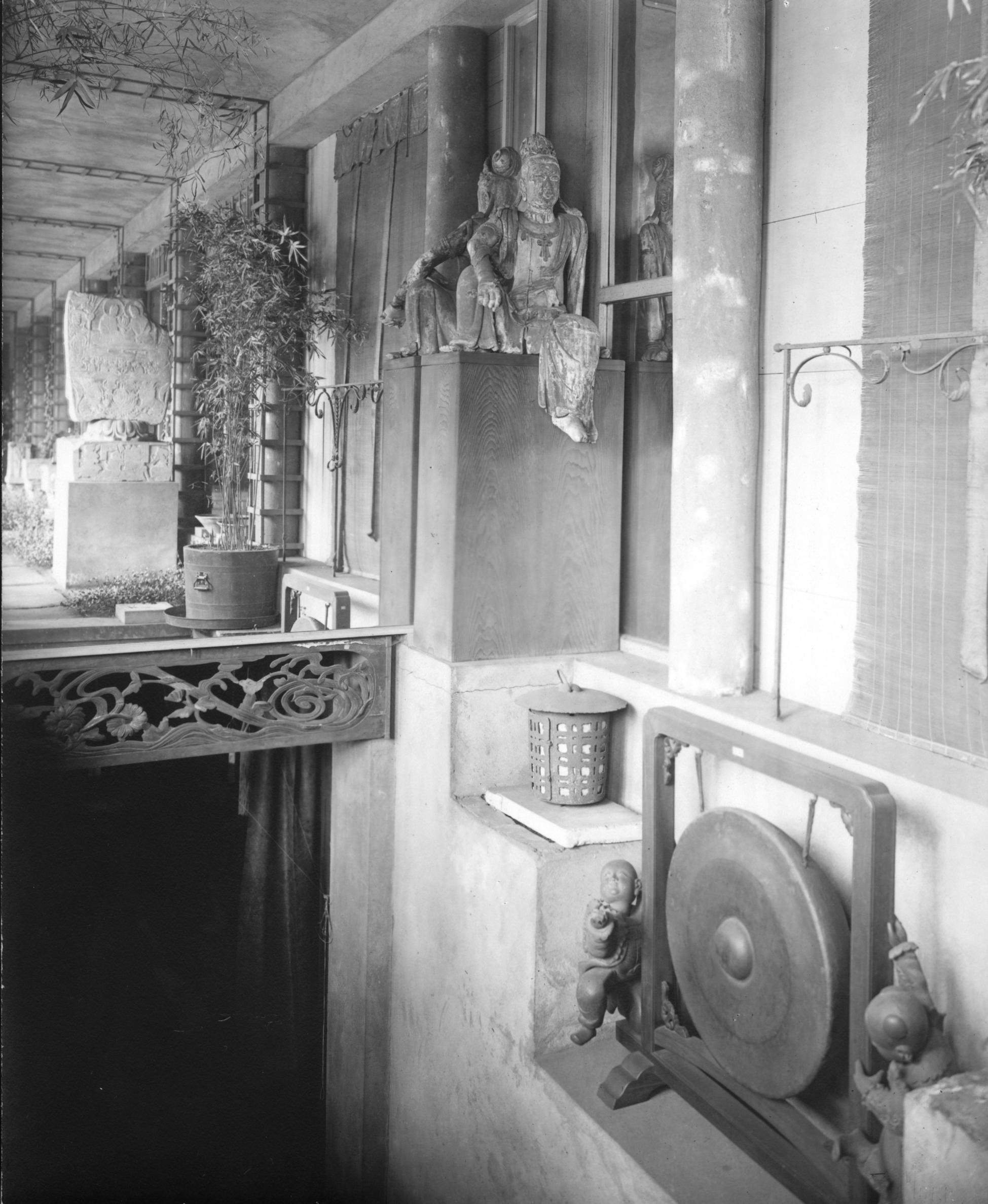 South-facing view of Chinese Loggia gallery from 1926 with the Guanyin sculpture prominently displayed above a staircase that is surrounded by Asian art.