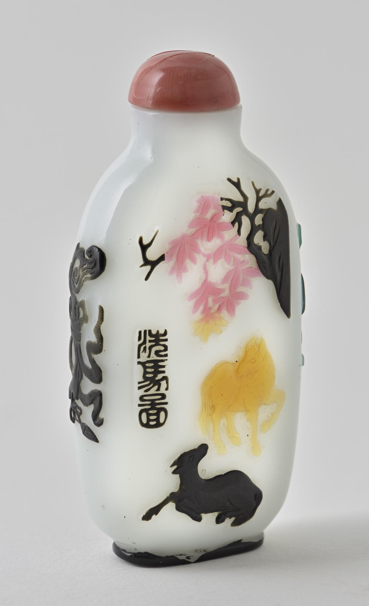  An oval-shaped snuff bottle with a red stopper. The body of the bottle is white with raised nature motifs, predominantly in black but also in pink and orange. 