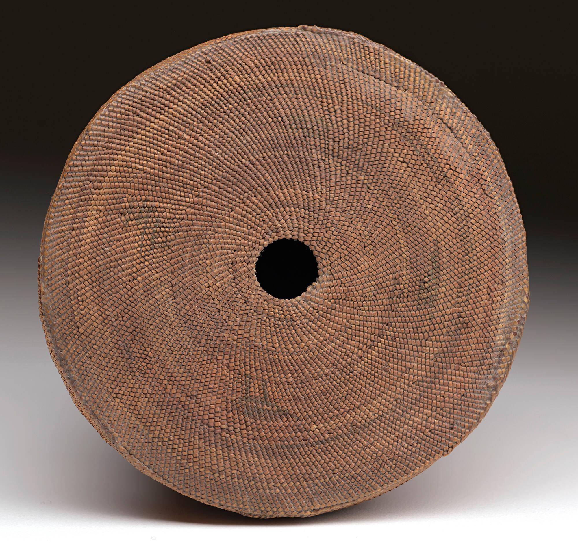 Lid of a small, woven Native American basket, with a hole in the center, made by a Makah weaver.