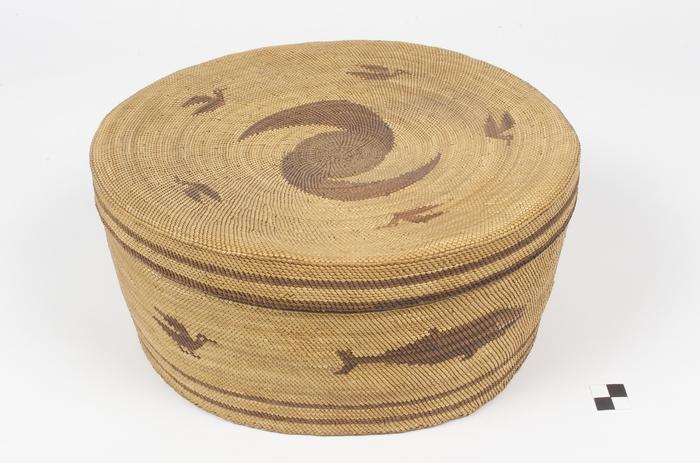 A lidded cylindrical woven basket with whale and bird motifs made by a Quileute weaver.