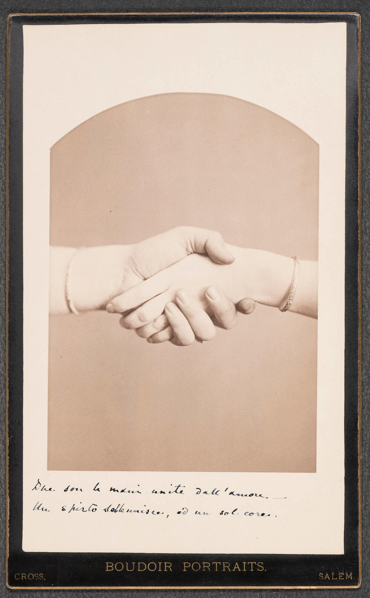 A photograph of two clasped light skinned hands of Crawford & Gardner. Inscribed in latin beneath the photograph is Two are the hands united in love, one spirit united and a single heart.