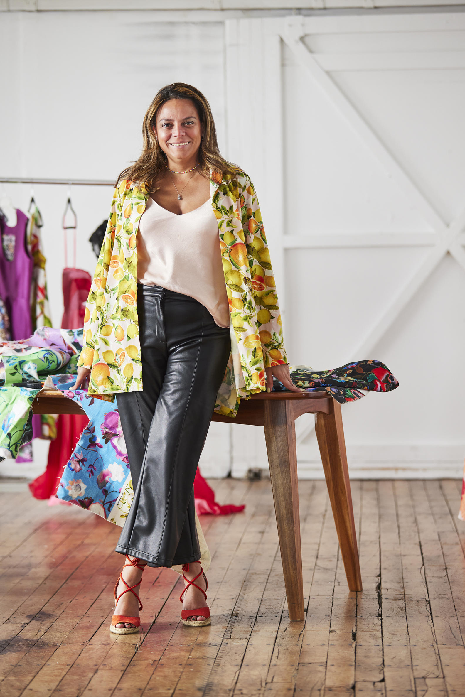 Melina standing in front of a table with fabrics draped all over it.